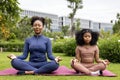 African American woman and her daughter in yoga suit are relaxingly practicing meditation exercise in the park to attain happiness