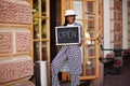 African american woman hold open welcome sign board in modern cafe coffee shop ready to service, restaurant, retail store, small