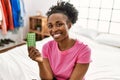 African american woman holding birth control pills sitting on bed at bedroom Royalty Free Stock Photo