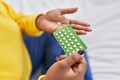 African american woman holding birth control pills sitting on bed at bedroom Royalty Free Stock Photo