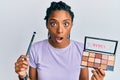 African american woman holding blush palette of nudes colors afraid and shocked with surprise and amazed expression, fear and