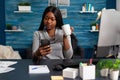 African american woman holding cup of coffee in hands socializing with friend using smartphone Royalty Free Stock Photo