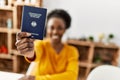 African american woman holding deutchland passport sitting on table at home Royalty Free Stock Photo