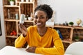 African american woman holding led light bulb sitting on table at home Royalty Free Stock Photo