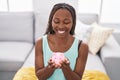 African american woman holding piggy bank sitting on sofa at home Royalty Free Stock Photo