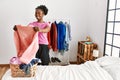 African american woman holding sweater doing laundry at bedroom Royalty Free Stock Photo