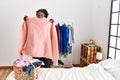 African american woman holding sweater doing laundry at bedroom Royalty Free Stock Photo