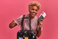 Happy african american woman holds tickets and shows that she is ready to travel.