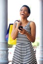 African american woman laughing with phone and shopping bags Royalty Free Stock Photo