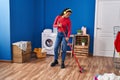 African american woman listening to music cleaning floor at laundry room Royalty Free Stock Photo