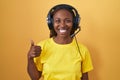 African american woman listening to music using headphones doing happy thumbs up gesture with hand Royalty Free Stock Photo