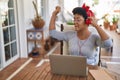 African american woman listneing to music sitting on table at home terrace Royalty Free Stock Photo