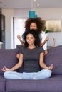 African American woman with little daughter practicing yoga at home