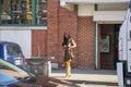 An African American woman with long sisterlocks wearing a brown and black dress, sunglasses and boots standing on the sidewalk Royalty Free Stock Photo
