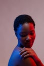 African american woman looking down with hand on shoulder in blue and red light, copy space Royalty Free Stock Photo