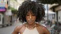 African american woman looking down with serious expression at coffee shop terrace Royalty Free Stock Photo