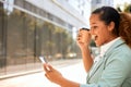 African American woman looking at the phone and holding a coffee mug is expressing extreme joy Royalty Free Stock Photo