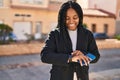 African american woman looking watch holding smartphone at park Royalty Free Stock Photo