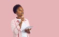 African American woman on pink copy space background thinking and writing in notebook Royalty Free Stock Photo