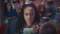 An African American woman is playing an online game on her phone, biting her lips from the tension. The girl's