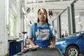 Exploring repairing. African american woman, professional female mechanic pulling, carrying tool box cart in auto repair