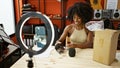African american woman radio reporter recording video unpacking microphone of cardboard box at radio studio Royalty Free Stock Photo