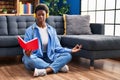 African american woman reading book doing yoga exersice sitting on floor at home