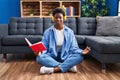 African american woman reading book doing yoga exersice sitting on floor at home