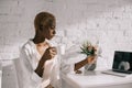 African american woman reading business newspaper and holding cup