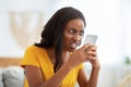 African American woman receiving bad news, angry at her smartphone at home