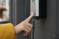 African-American woman ringing intercom with camera near building entrance, closeup