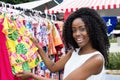 African american woman selling colorful clothes at market