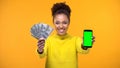 African-American woman showing smartphone and bunch of dollars, money transfer