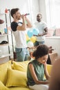 african american woman sitting on sofa and two young men standing behind with party horns and colorful