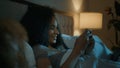 African American woman sleepless girl happy insomniac teen playing online game illuminated with mobile phone screen on