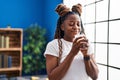 African american woman smelling aromatic candle standing at home