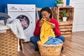 African american woman smelling towel washing clothes at laundry room Royalty Free Stock Photo