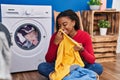 African american woman smelling towel washing clothes at laundry room Royalty Free Stock Photo