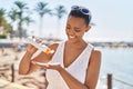 African american woman smiling confident applying sunscreen lotion at seaside Royalty Free Stock Photo