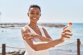 African american woman smiling confident applying sunscreen lotion at seaside Royalty Free Stock Photo