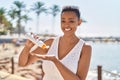 African american woman smiling confident applying sunscreen lotion at seaside Royalty Free Stock Photo