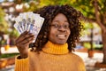 African american woman smiling confident holding rands banknotes at park Royalty Free Stock Photo