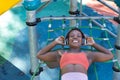 African American woman in sports clothes and white headphones, lying down and smiling, listening to music in a playground. Concept Royalty Free Stock Photo