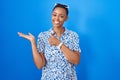 African american woman standing over blue background showing palm hand and doing ok gesture with thumbs up, smiling happy and Royalty Free Stock Photo