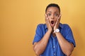 African american woman standing over yellow background afraid and shocked, surprise and amazed expression with hands on face Royalty Free Stock Photo