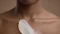 African American Woman Stroking Skin With Feather, Beige Background, Cropped