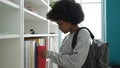 African american woman student holding book of shelving at library university Royalty Free Stock Photo