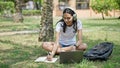 African american woman student using laptop and headphones taking notes at university campus Royalty Free Stock Photo