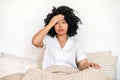 african american woman with headache sitting in bed Royalty Free Stock Photo