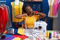 African american woman tailor stressed using sewing machine at sewing studio Royalty Free Stock Photo